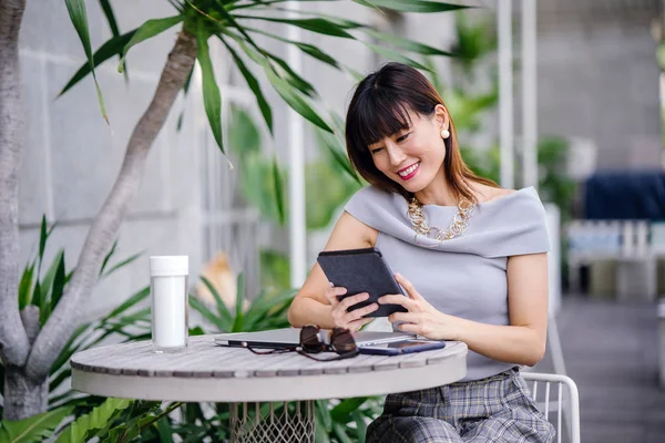 Çekici, kendine güvenen ve başarılı bir Çinli Asyalı kadının portresi. Akıllı telefonunu tutuyor. 
