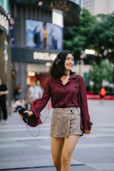 şık bir bluz ve şort olarak o yürür onu kulaklık ile şehirde bir sokakta dans güzel Koreli kadın