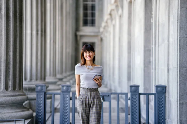 Çekici, kendine güvenen ve başarılı bir Çinli Asyalı kadının portresi. Akıllı telefonunu tutuyor. 