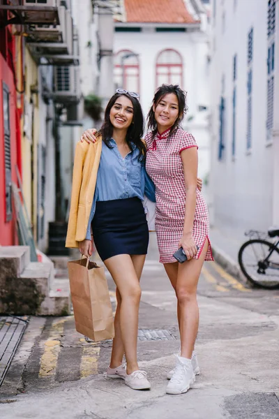 iki yakın arkadaş birlikte bir ara Sokaktan yürürken. Onlar birlikte mutlu bir şekilde yürürken onlar hem trendy retro giyim ve tutuşup giyiyorsun. Çince, diğer Hint biri