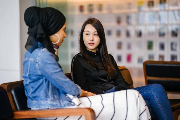 Duas Amigas Sentadas Banco Conversando Uma Delas Chinesa Outra Muçulmana — Fotografia de Stock