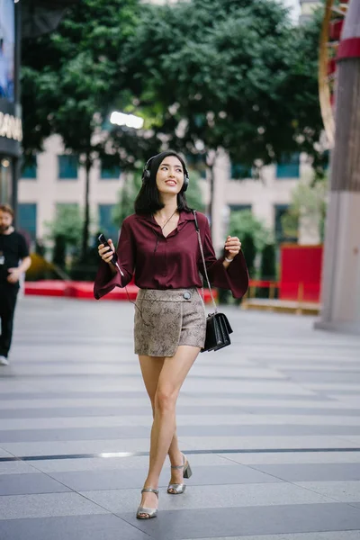 şık bir bluz ve şort olarak o yürür onu kulaklık ile şehirde bir sokakta dans güzel Koreli kadın
