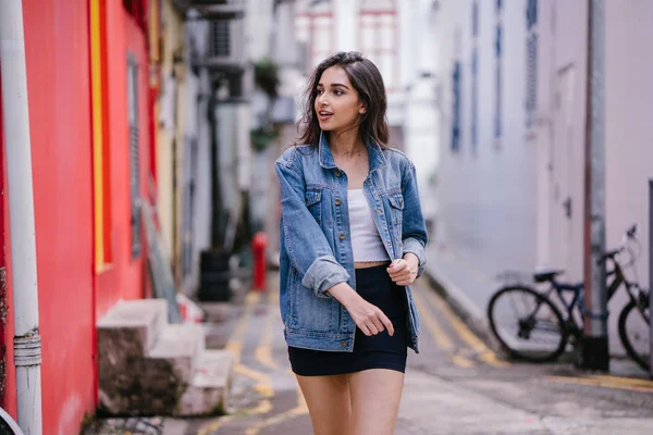 gün boyunca şehrin sokakta yürürken uzun boylu, genç ve zarif Hint Asyalı bir kadın. O bir retro Kot ceket giyiyor