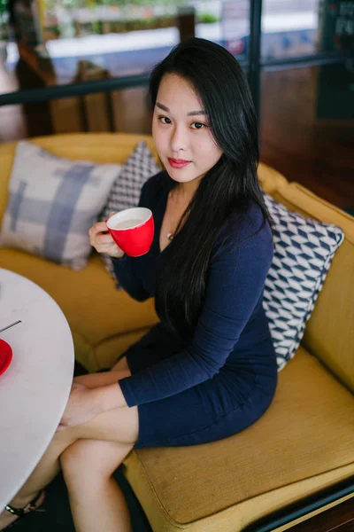 Bir açık havada açık havada oturan ve kırmızı bir çay seti çay sıcak bir fincan zevk genç, çekici, zarif ve güzel Asyalı kadın Portresi. 