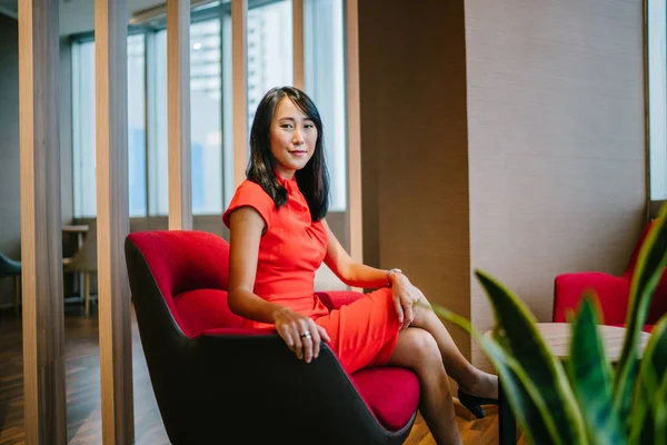 Sandalyede Oturan Güzel Kırmızı Elbiseli Asyalı Kadının Portresi — Stok fotoğraf