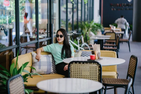 週末の日中はカフェでくつろいだり くつろいだりする若くて魅力的な中国系アジア人女性の肖像画 彼女はミントグリーンのセーターを着ている — ストック写真