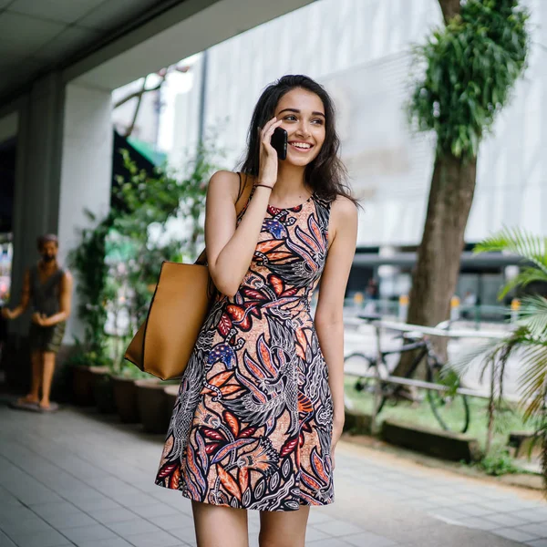 立っていると日中にアジアの都市の都市通りにスマート フォンで話す若いインド人のアジア女性 — ストック写真