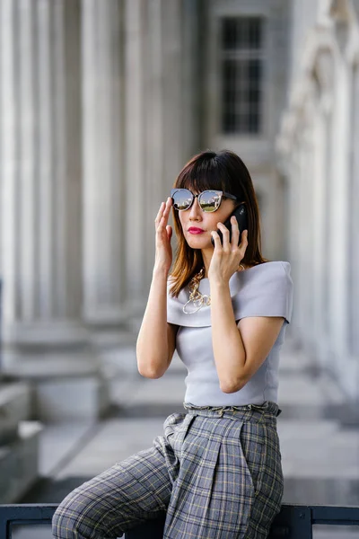 Çekici, kendine güvenen ve başarılı bir Çinli Asyalı kadının portresi. Akıllı telefonuyla konuşuyor. 