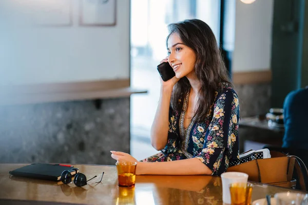 Bir kafede onu smartphone o görüşmeler olarak gündüzleri çatık bir genç ve çekici Hint Asyalı kadın portresi