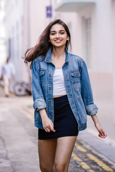 gün boyunca şehrin sokakta yürürken uzun boylu, genç ve zarif Hint Asyalı bir kadın. O bir retro Kot ceket giyiyor