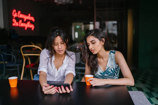 İki yakın arkadaş (kadınlar) gün boyunca bir kafede oturup bir video birlikte Smartphone'da izlerim. Video ve birbirlerinin şirket zevk olarak her ikisi de gülüyorsun.