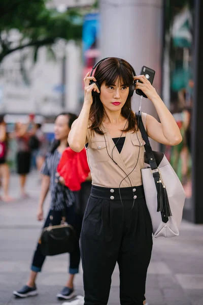 Onun kulaklık müzik dinlemek orta yaşlı, fotojenik bir Çinli kadın portresi