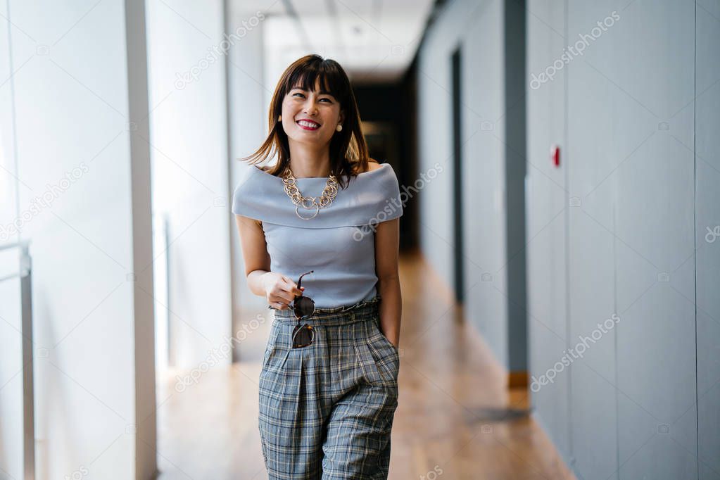 Portrait of a middle-aged, mature Asian Chinese woman in smart casual grey outfit