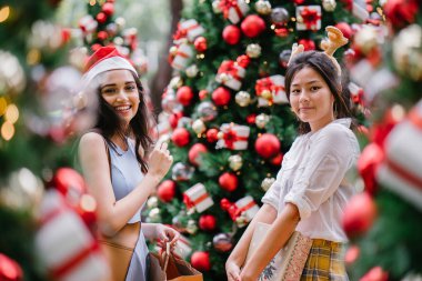 İki genç Asyalı kızlar exchange bir başka gün boyunca şehrin bir sokakta bir şekilde dekore edilmiş bir Noel ağacı altında sunuyor. Hint, diğer Çinli biri