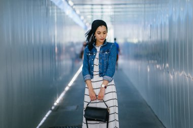 Genç, zarif ve çekici Malezyalı Müslüman kadın gün boyunca elbise ve kot ceket giyiyor..