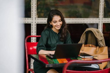 genç üniversite öğrencisi (Hint Asyalı kadın) eğitim ve gün boyunca dizüstü bilgisayar bir masa başında çalışma