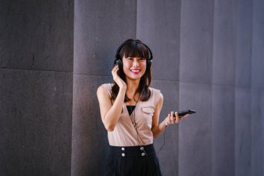 Onun kulaklık müzik dinlemek orta yaşlı, fotojenik bir Çinli kadın portresi