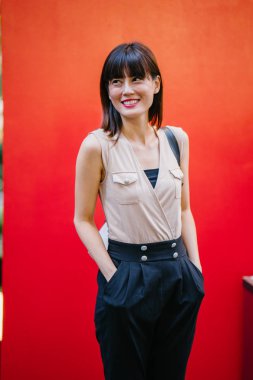 Bir çalışma hanım o pozlar ve onun baş shot kırmızı bir arka plan için gülümsüyor olarak stüdyo portresi