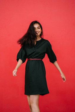 Stüdyo bir güzel, Genç ve çekici Hint Asyalı kadın kırmızı studio çerçevede bir portresi. O zarif bir basit yeşil elbise ve kırmızı kuşak giymiş ve gülüyor.