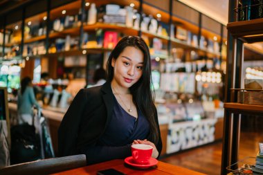 Bir açık havada açık havada oturan ve kırmızı bir çay seti çay sıcak bir fincan zevk genç, çekici, zarif ve güzel Asyalı kadın Portresi. 