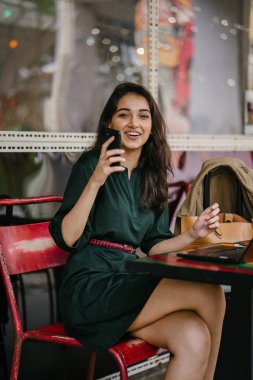 Genç Singpaorean Kızılderili kadın eğitim ya da bir kafede gün boyunca onu laptop çalışan bir mola alır gibi onun smartphone kontrol