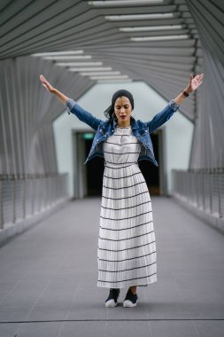 Genç, zarif ve çekici Malezyalı Müslüman kadın gün boyunca elbise ve kot ceket giyiyor..