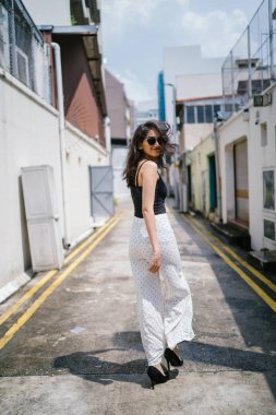 Genç, uzun boylu, ince ve zarif Hint Asyalı kadın rahat bir kıyafet içinde Asya bir sokakta bir sokakta aşağı gün boyunca yürür