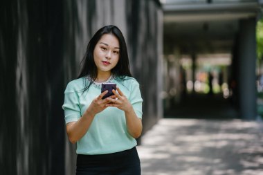 Akıllı telefon tutan genç ve güzel Asyalı bir Çinli kadının portresi.