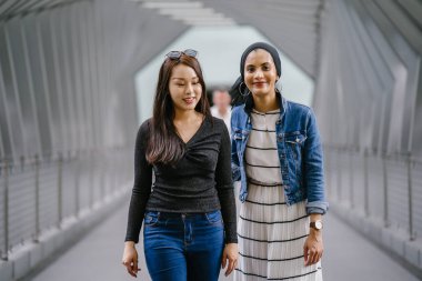 Gündüz vakti köprüde farklı etnik kökenlere sahip iki arkadaş. Biri Malezyalı Müslüman bir kadın, diğeri de Çinli bir Asyalı. İkisi de genç, enerjik ve çekici..