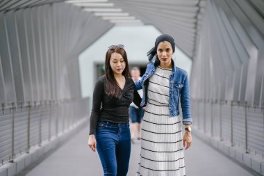 Gündüz vakti köprüde farklı etnik kökenlere sahip iki arkadaş. Biri Malezyalı Müslüman bir kadın, diğeri de Çinli bir Asyalı. İkisi de genç, enerjik ve çekici..