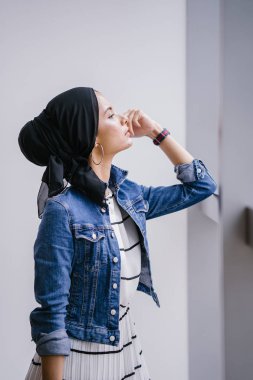 Genç, zarif ve çekici Malezyalı Müslüman kadın gün boyunca elbise ve kot ceket giyiyor..