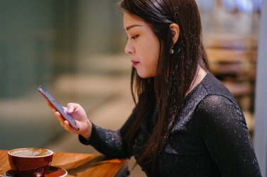 Kafede tablet bilgisayar kullanan genç bir kadın.