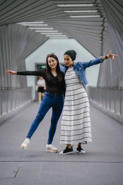 Gündüz vakti köprüde farklı etnik kökenlere sahip iki arkadaş. Biri Malezyalı Müslüman bir kadın, diğeri de Çinli bir Asyalı. İkisi de genç, enerjik ve çekici..