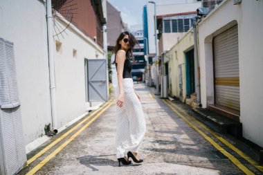 Genç, uzun boylu, ince ve zarif Hint Asyalı kadın rahat bir kıyafet içinde Asya bir sokakta bir sokakta aşağı gün boyunca yürür