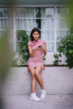 Bir genç, çok-cool-için-okulu Asya retro kırmızı ve beyaz cheongsam genç kız elbise gün boyunca bir kenarında oturan Çin moda portre