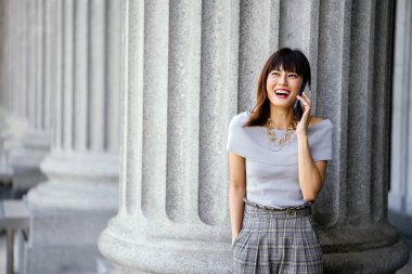 Çekici, kendine güvenen ve başarılı bir Çinli Asyalı kadının portresi. Akıllı telefonunu tutuyor. 