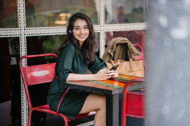 Genç Hintli Asyalı kadın o onun Smartphone-e doğru onun kulaklık streaming müzik hoşlanır