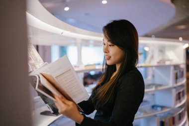 Sadece halk kütüphanesinde kitap okuyan Çinli bir Asyalı kadının portresi..