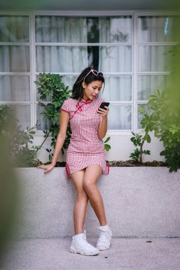 Bir genç, çok-cool-için-okulu Asya retro kırmızı ve beyaz cheongsam genç kız elbise gün boyunca bir kenarında oturan Çin moda portre
