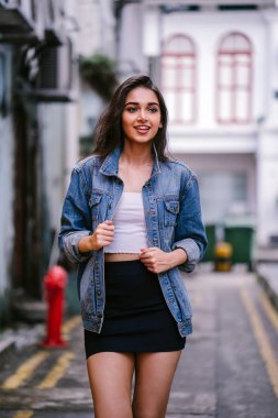 gün boyunca şehrin sokakta yürürken uzun boylu, genç ve zarif Hint Asyalı bir kadın. O bir retro Kot ceket giyiyor