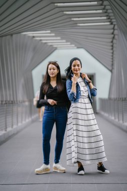 Gündüz vakti köprüde farklı etnik kökenlere sahip iki arkadaş. Biri Malezyalı Müslüman bir kadın, diğeri de Çinli bir Asyalı. İkisi de genç, enerjik ve çekici..