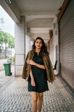 Hint Asyalı kadın Genç, uzun boylu, ince ve zarif bir portre için poz veriyor. O rahat ve şık rahat giysiler giyiyor ve bir adamın ceketi omuzları üzerinde bol dökümlü vardır. 