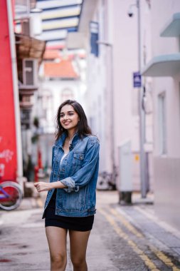 gün boyunca şehrin sokakta yürürken uzun boylu, genç ve zarif Hint Asyalı bir kadın. O bir retro Kot ceket giyiyor