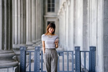 Çekici, kendine güvenen ve başarılı bir Çinli Asyalı kadının portresi. Akıllı telefonunu tutuyor. 