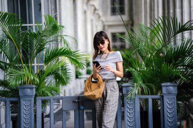 Çekici, kendine güvenen ve başarılı bir Çinli Asyalı kadının portresi. Akıllı telefonunu tutuyor. 