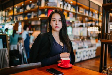 Bir açık havada açık havada oturan ve kırmızı bir çay seti çay sıcak bir fincan zevk genç, çekici, zarif ve güzel Asyalı kadın Portresi. 