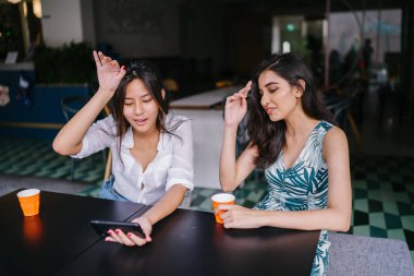 İki yakın arkadaş (kadınlar) gün boyunca bir kafede oturup bir video birlikte Smartphone'da izlerim. Video ve birbirlerinin şirket zevk olarak her ikisi de gülüyorsun.