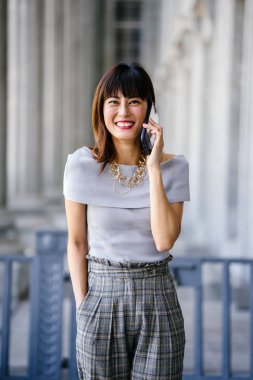 Çekici, kendine güvenen ve başarılı bir Çinli Asyalı kadının portresi. Akıllı telefonuyla konuşuyor. 
