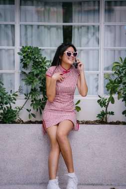 Bir şık, güzel ve genç genç Asyalı kız onun smartphone üzerinde konuşuyor. Geleneksel Çince elbise giyiyor 