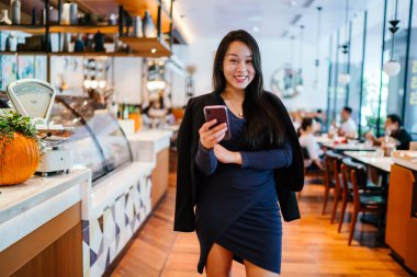 Akıllı telefon tutan genç ve güzel Asyalı bir Çinli kadının portresi.